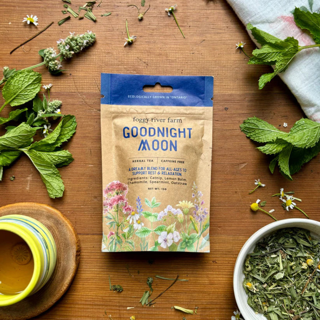 Goodnight Moon tea package on a wooden surface with herbs and a cup.