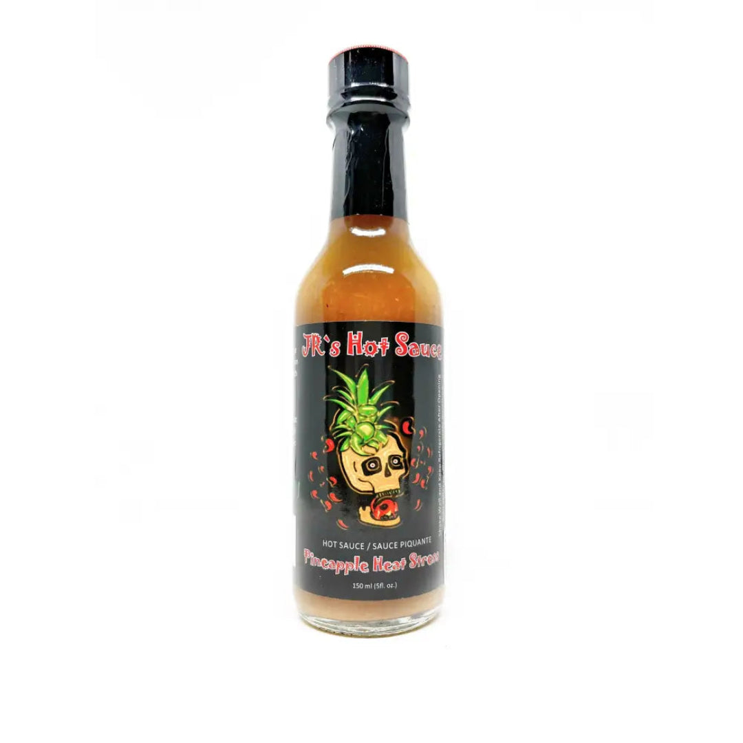 Bottle of pineapple heat sauce with a black label on a white background