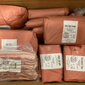 Packages of honey garlic sausage and bacon in a cardboard box with labels.
