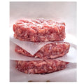 Three raw ground meat patties stacked on a white surface with wax paper underneath.